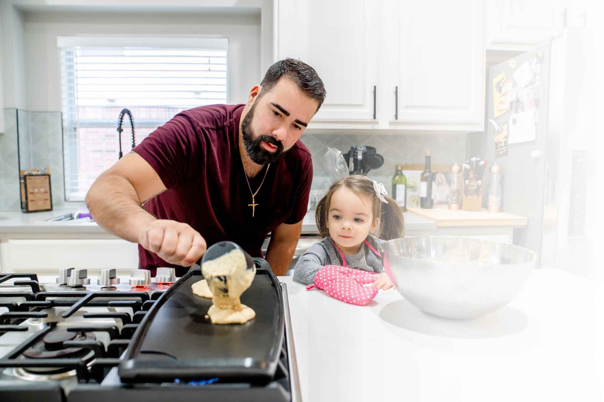 Un padre haciendo panqueques con su hija en la cocina